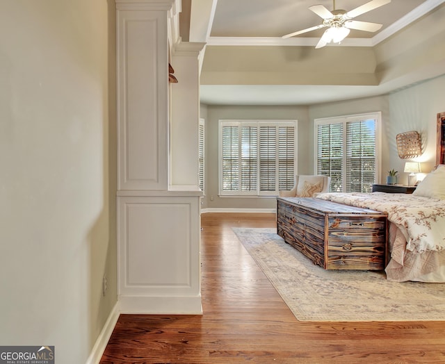 bedroom with a raised ceiling, ceiling fan, wood-type flooring, and ornamental molding