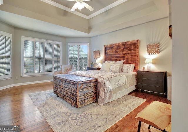 bedroom with ceiling fan, dark hardwood / wood-style flooring, a raised ceiling, and ornamental molding