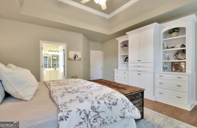 bedroom with ceiling fan, dark hardwood / wood-style floors, ensuite bathroom, and a tray ceiling