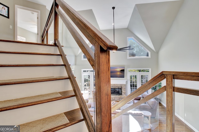 stairway with a fireplace, french doors, and high vaulted ceiling