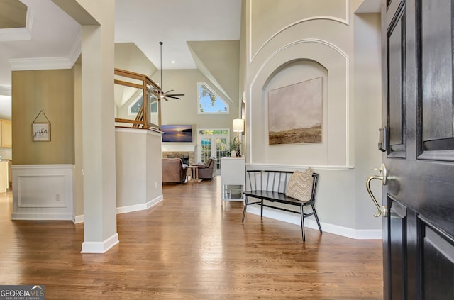 foyer entrance with a fireplace, dark hardwood / wood-style flooring, ceiling fan, and crown molding