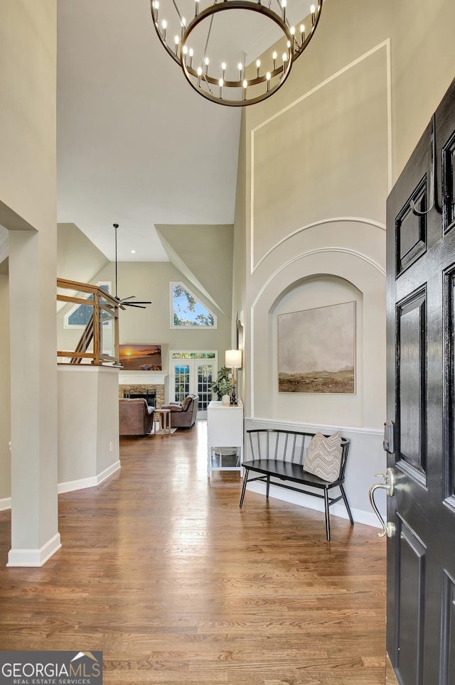 entryway featuring a towering ceiling, wood-type flooring, and ceiling fan with notable chandelier