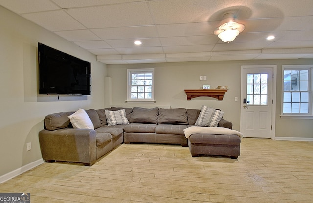 living room featuring a drop ceiling and light hardwood / wood-style flooring