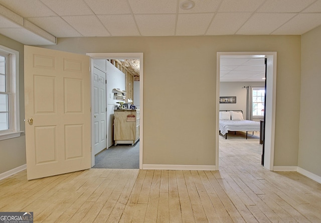 corridor featuring a paneled ceiling and light hardwood / wood-style flooring