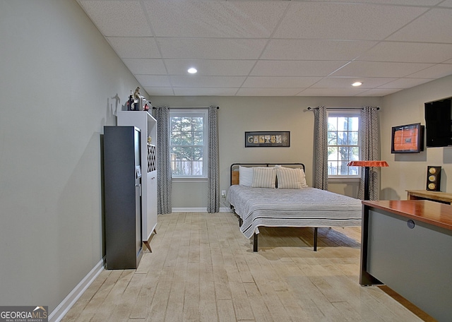 bedroom with a drop ceiling and light hardwood / wood-style floors