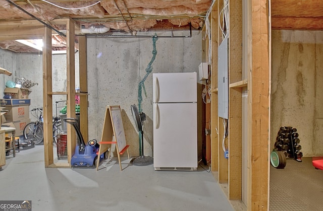 basement featuring white refrigerator and electric panel