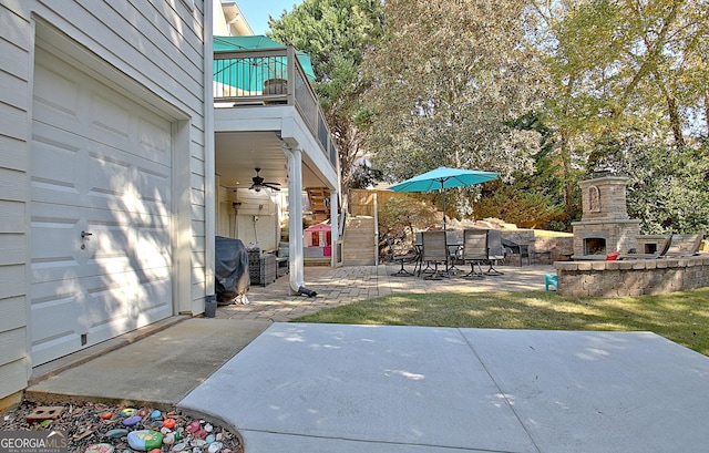 view of patio with an outdoor stone fireplace, ceiling fan, a balcony, and grilling area