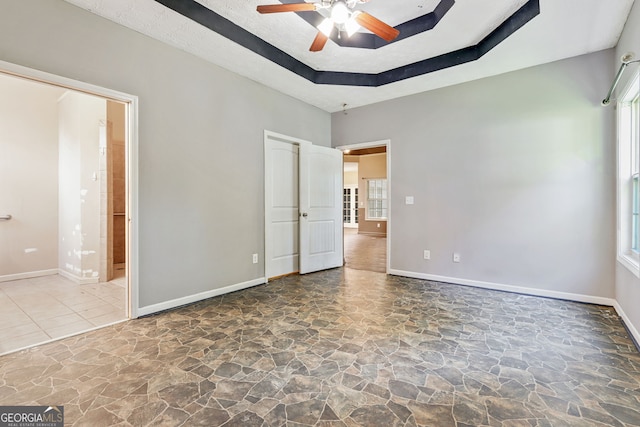 unfurnished bedroom with ceiling fan and a raised ceiling