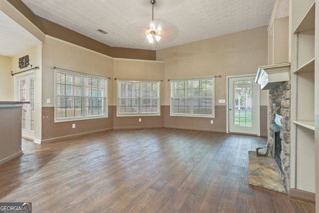 unfurnished living room featuring a textured ceiling, ceiling fan, a fireplace, and dark wood-type flooring