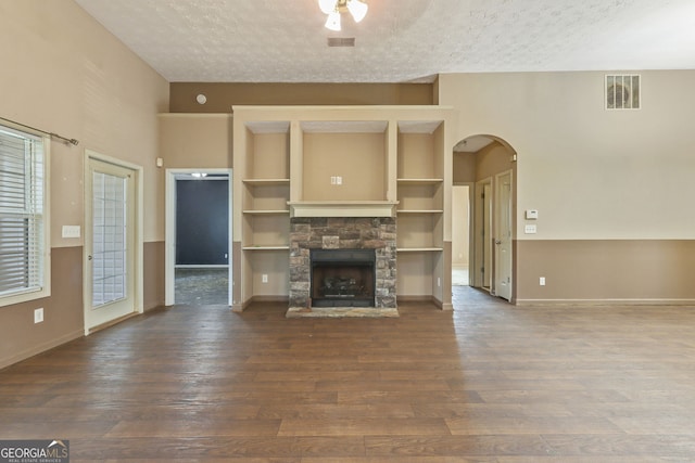 unfurnished living room featuring a textured ceiling, a healthy amount of sunlight, and a stone fireplace