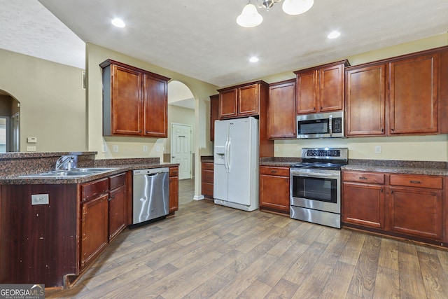 kitchen featuring sink, stainless steel appliances, hanging light fixtures, and dark hardwood / wood-style floors