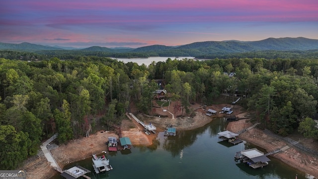 aerial view at dusk featuring a water and mountain view