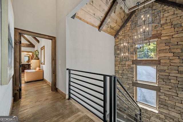 hallway featuring wood-type flooring, wood ceiling, beam ceiling, high vaulted ceiling, and a chandelier