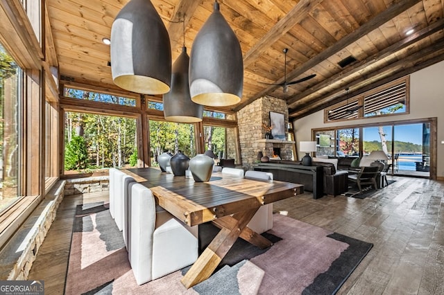 dining room with a stone fireplace, wood ceiling, beamed ceiling, high vaulted ceiling, and dark hardwood / wood-style flooring