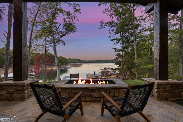 patio terrace at dusk with a water view and a fire pit