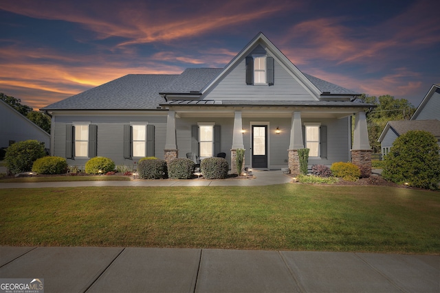 view of front of house with covered porch and a lawn