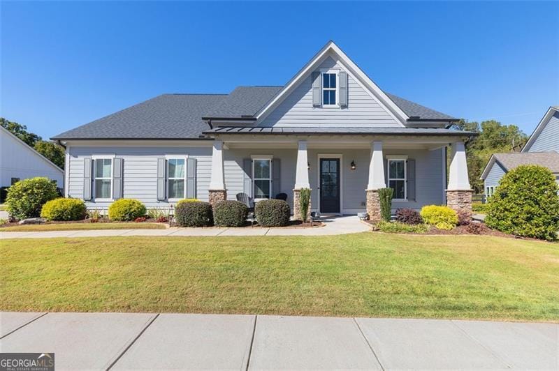 view of front of home featuring a standing seam roof, metal roof, covered porch, and a front yard