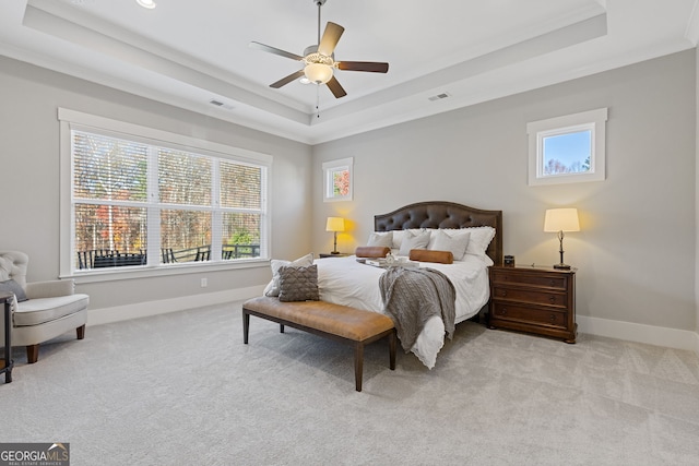 carpeted bedroom with a tray ceiling and baseboards