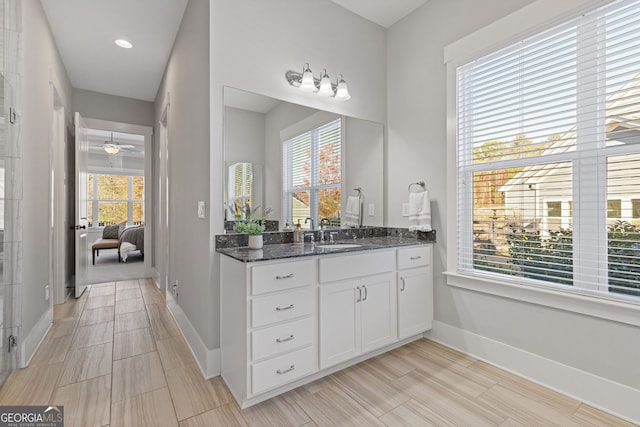 full bathroom with ceiling fan, connected bathroom, vanity, and baseboards