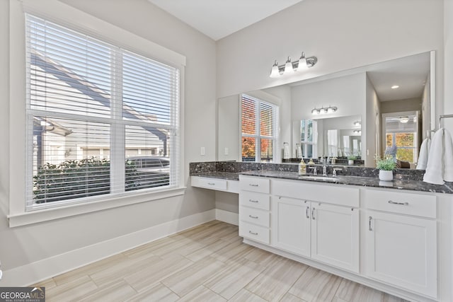 bathroom with plenty of natural light, baseboards, ceiling fan, and vanity