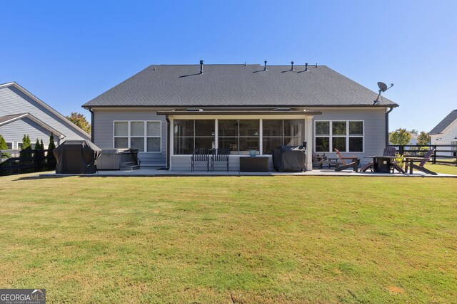 rear view of property with a yard, a hot tub, a patio area, and a sunroom