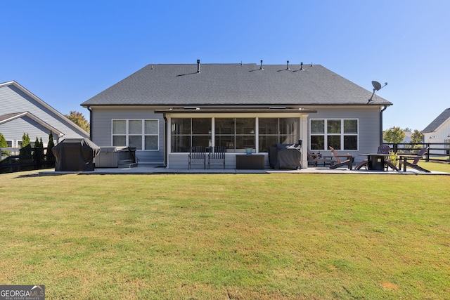 rear view of property featuring a yard, a hot tub, a sunroom, and a patio