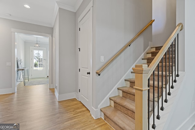 staircase with crown molding, baseboards, wood finished floors, and recessed lighting