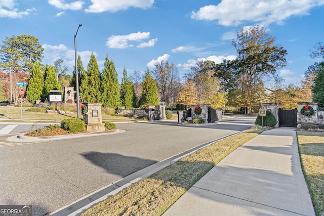 view of road with sidewalks, a gate, a gated entry, and curbs