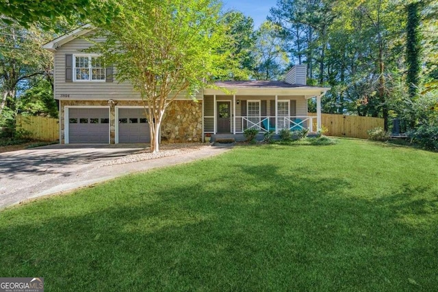 split level home with covered porch, a front lawn, and a garage