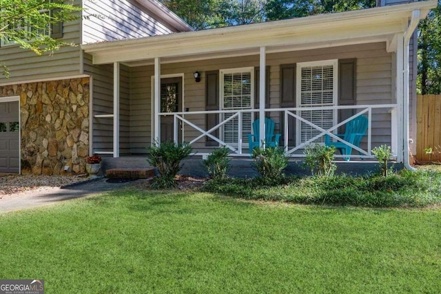 entrance to property featuring covered porch and a lawn