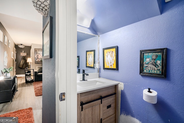 bathroom with vanity, wood-type flooring, and vaulted ceiling