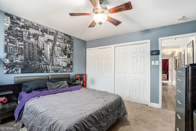 bedroom with two closets, carpet, and ceiling fan