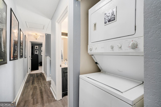 washroom featuring dark hardwood / wood-style floors and stacked washing maching and dryer