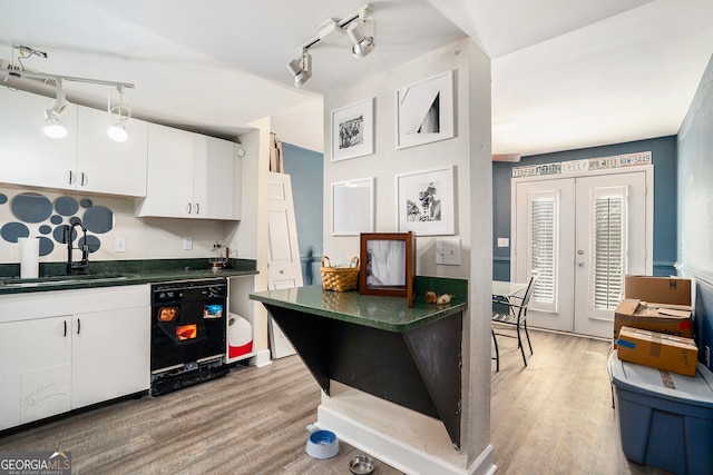 kitchen featuring black dishwasher, sink, white cabinets, and light wood-type flooring