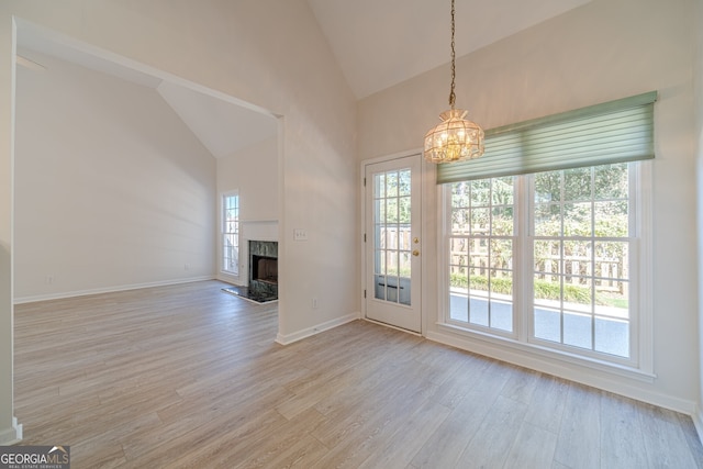 unfurnished living room featuring high vaulted ceiling, a chandelier, and light hardwood / wood-style flooring