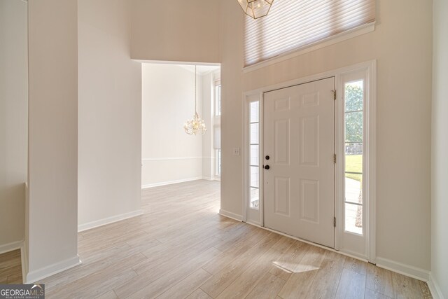 entrance foyer with a high ceiling, light wood-type flooring, and a notable chandelier