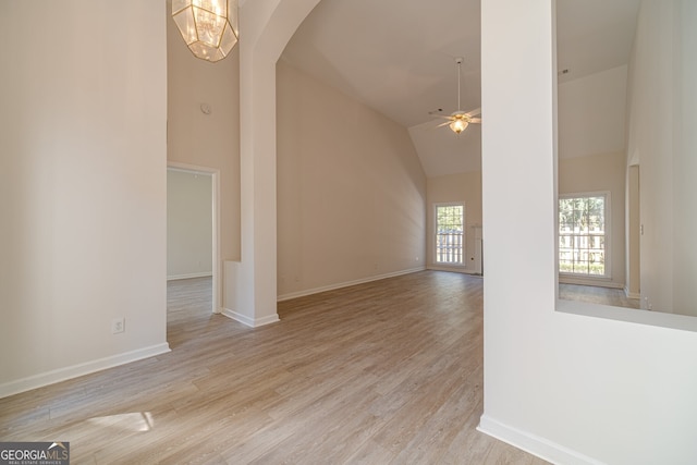 interior space featuring light hardwood / wood-style floors, ceiling fan with notable chandelier, and high vaulted ceiling