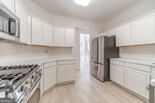 kitchen with light hardwood / wood-style floors, white cabinetry, and appliances with stainless steel finishes