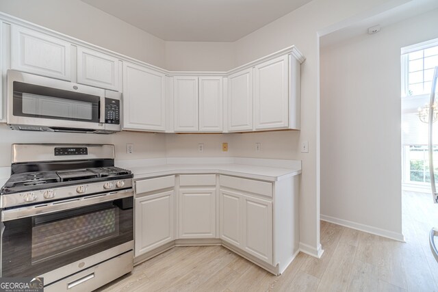 kitchen featuring white cabinetry, light wood-type flooring, stainless steel appliances, and a healthy amount of sunlight