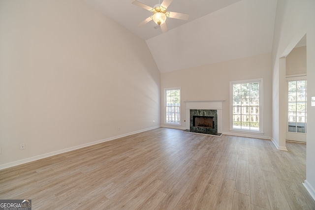 unfurnished living room featuring a wealth of natural light, a high end fireplace, ceiling fan, and light hardwood / wood-style flooring