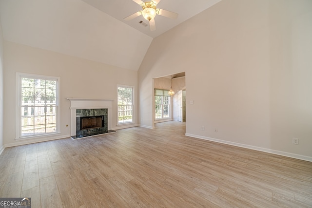 unfurnished living room featuring ceiling fan, a wealth of natural light, a high end fireplace, and light hardwood / wood-style floors