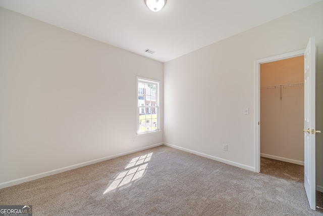 unfurnished bedroom featuring a closet, a spacious closet, and light colored carpet