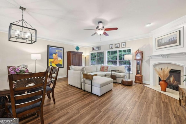 living room with hardwood / wood-style floors, ceiling fan with notable chandelier, and ornamental molding