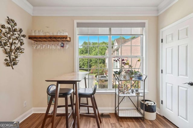 dining room featuring ornamental molding, bar area, and hardwood / wood-style flooring