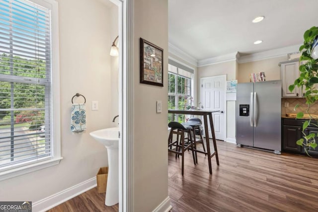 kitchen with hardwood / wood-style floors, crown molding, backsplash, and stainless steel fridge