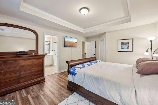 bedroom featuring ensuite bathroom, hardwood / wood-style flooring, crown molding, and a tray ceiling