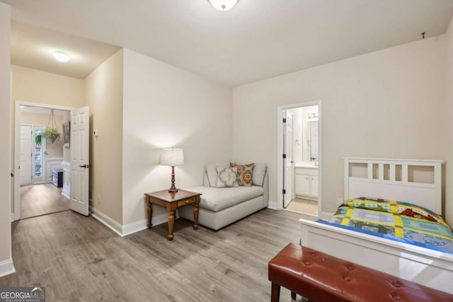 bedroom featuring connected bathroom and light wood-type flooring