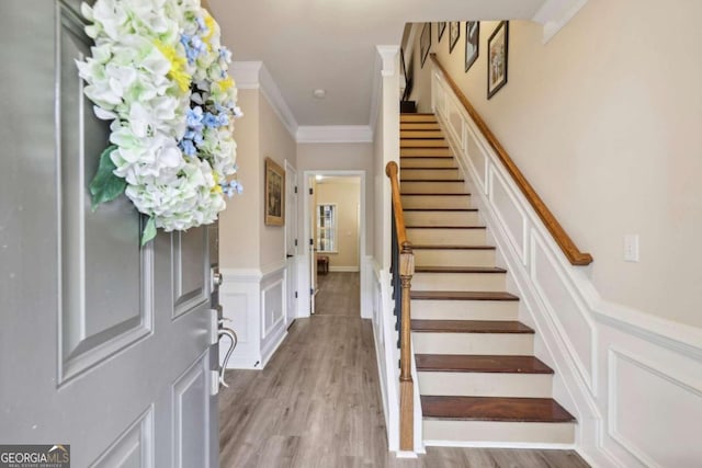 entryway with light wood-type flooring and crown molding