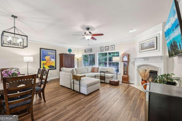 living room with dark hardwood / wood-style floors, ceiling fan with notable chandelier, and ornamental molding