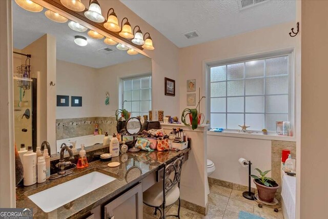 bathroom with a bathing tub, a textured ceiling, toilet, vanity, and tile patterned floors